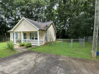 A charming cottage residence with a quaint front porch and ample yard space.