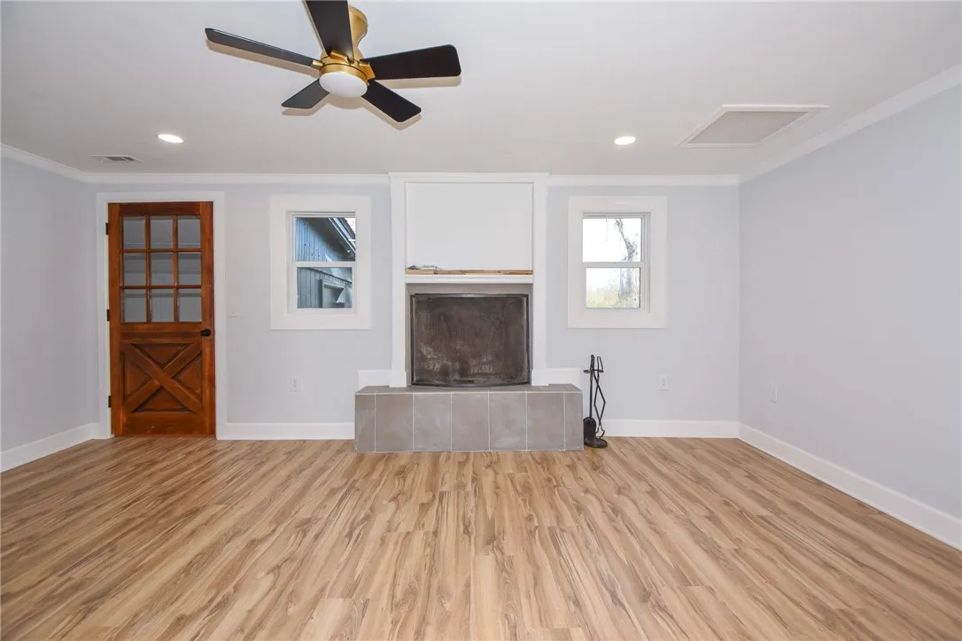 A well-lit living area showcases a tiled fireplace and warm wood flooring.