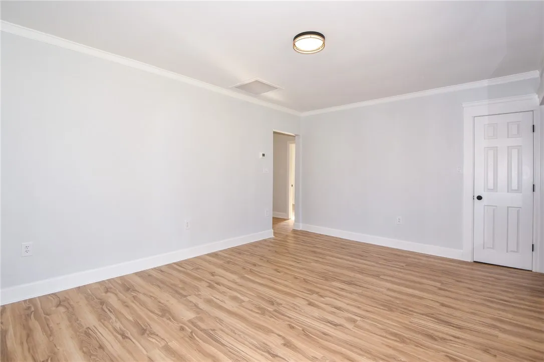 Smooth wood-look flooring extends throughout this versatile, airy interior space, crowned with crisp white trim.