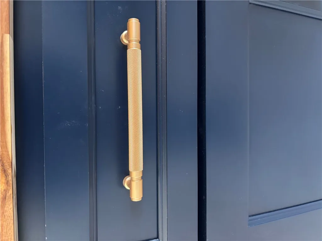 A striking brass handle accents the dark, rich entryway.