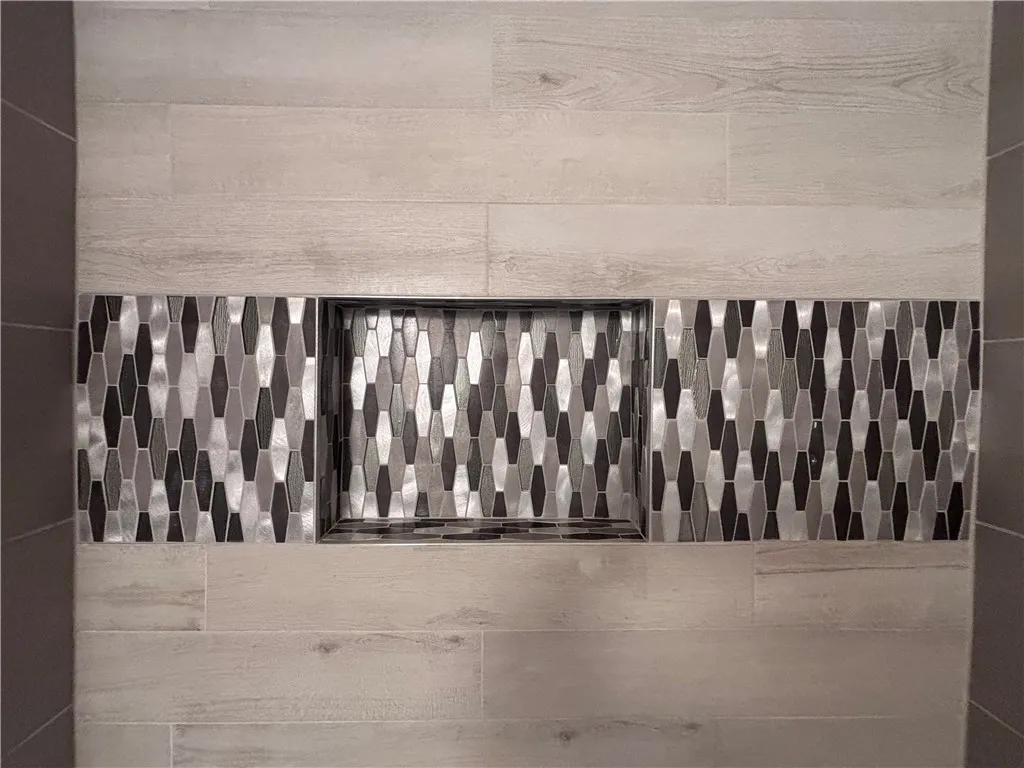 Artisan tile patterns and recessed shelving enhance this sophisticated shower's design.