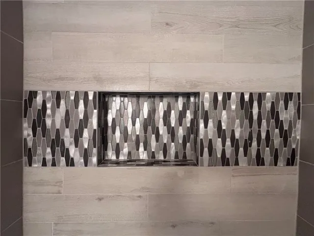 Artisan tile patterns and recessed shelving enhance this sophisticated shower's design.