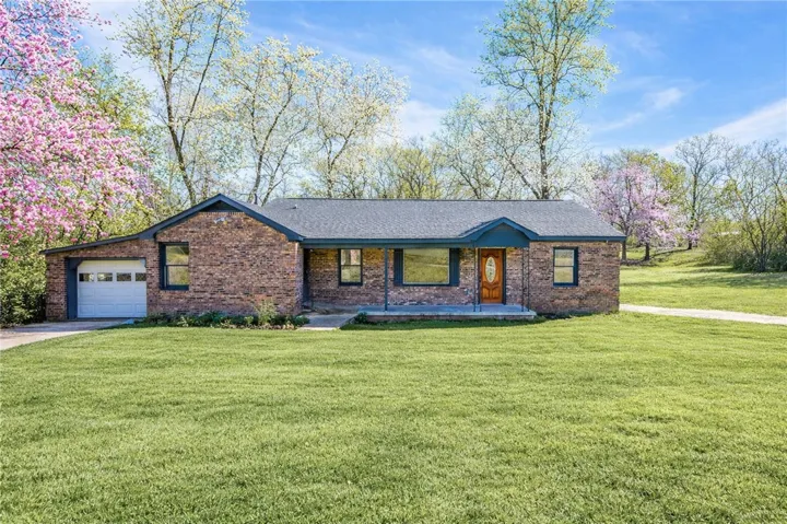 A classic brick ranch-style home set against a backdrop of mature trees, featuring a welcoming front porch.