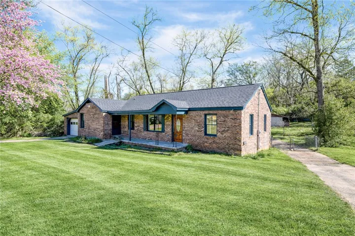 A charming brick ranch home presents a generous lawn and covered front porch, awaiting your personal touch.