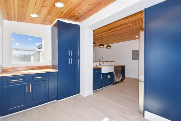 A well-appointed kitchen features rich blue cabinetry and a warm wood plank ceiling.