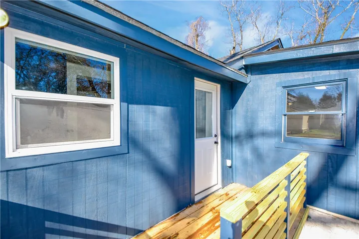 A vibrant blue exterior with a white entry door and a natural wood ramp, offering easy access.