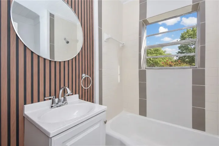 A well-lit primary bathroom with modern fixtures and a vibrant window view.