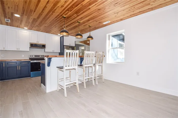A striking kitchen with a rich wood plank ceiling and stylish pendant lights over a practical breakfast bar.