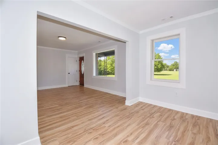 Step into this luminous living area, featuring light wood flooring and wide windows overlooking a green landscape.