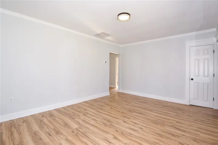Smooth wood-look flooring extends throughout this versatile, airy interior space, crowned with crisp white trim.