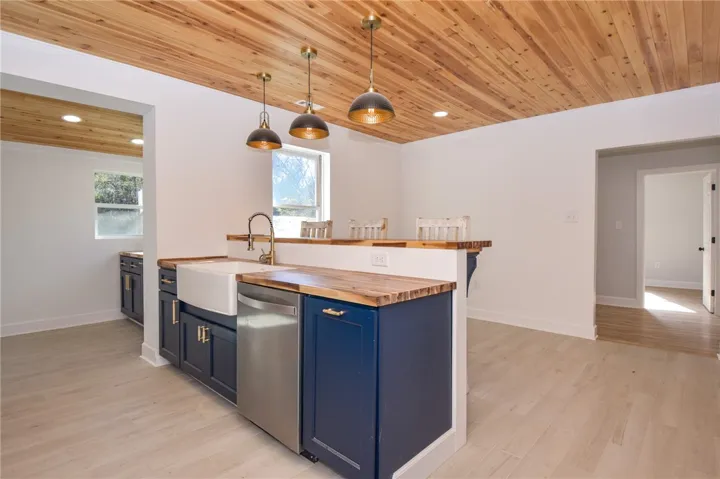Custom cabinetry and hardwood ceiling planks define this inviting, open-concept kitchen with a breakfast bar.