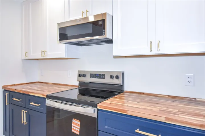 Butcher block countertops complement modern cabinetry and stainless steel appliances in this functional kitchen.