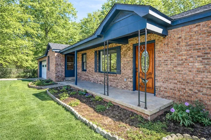 A classic brick facade welcomes with a covered porch and charming landscaping.