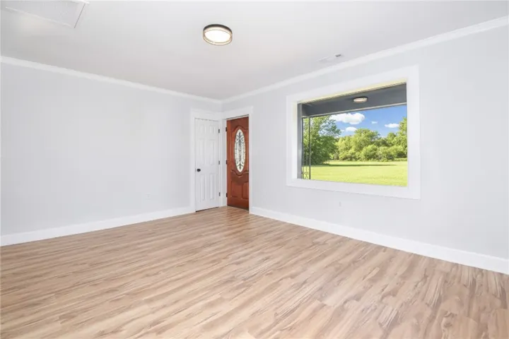 A well-lit entry welcomes with rich wood flooring and a view of nature.