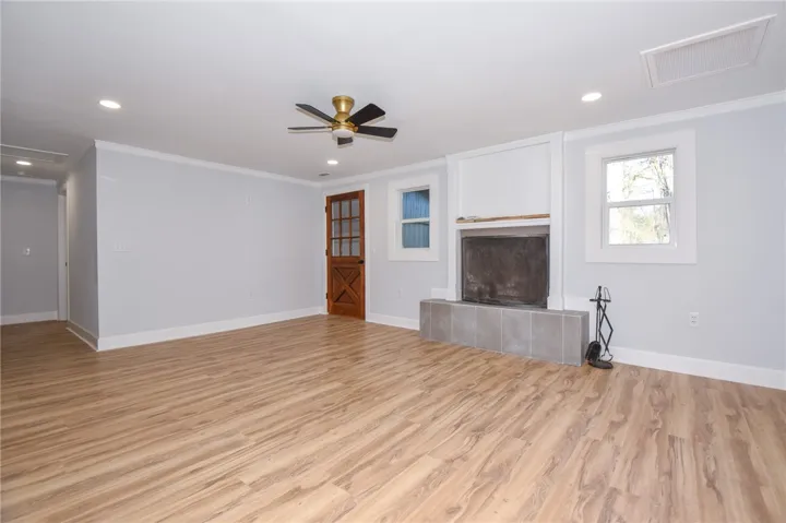A welcoming living area featuring durable wood flooring and a cozy fireplace with a tiled hearth.