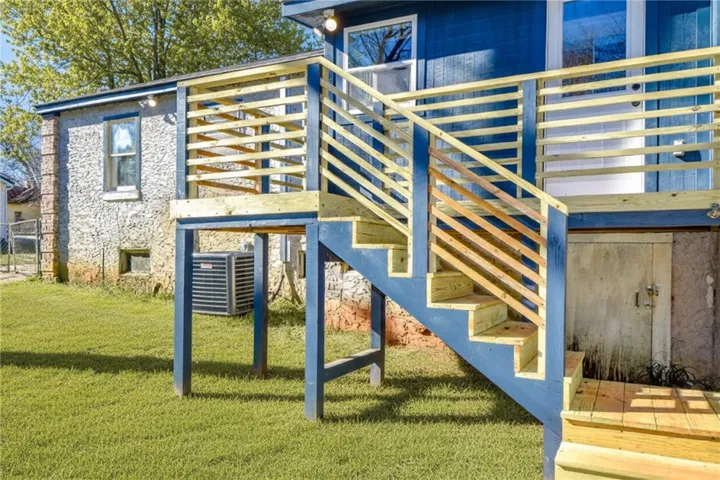 A newly constructed wooden deck and stairs provide elevated access to this vibrant blue home.