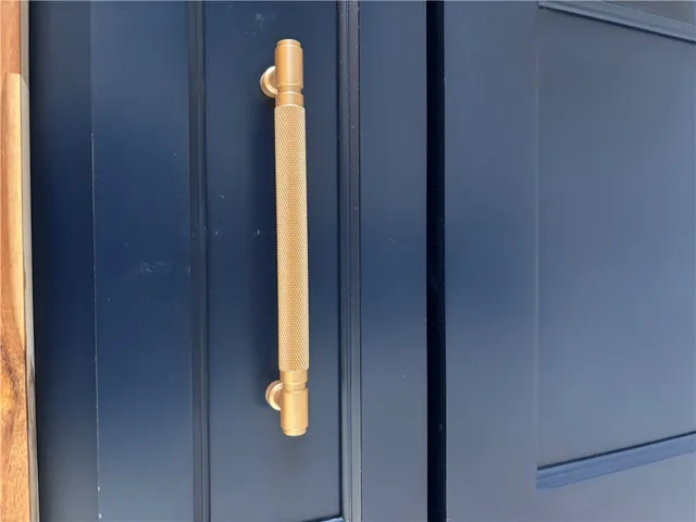 A striking brass handle accents the dark, rich entryway.