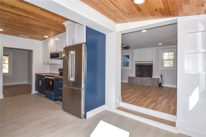 A streamlined kitchen flows into an inviting living area, showcasing warm wood ceilings and modern finishes.