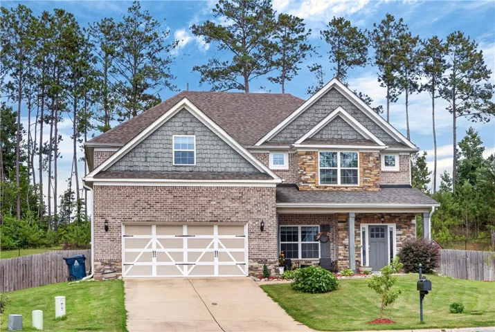 A classic brick and stone facade welcomes you to this inviting residence, framed by mature trees.