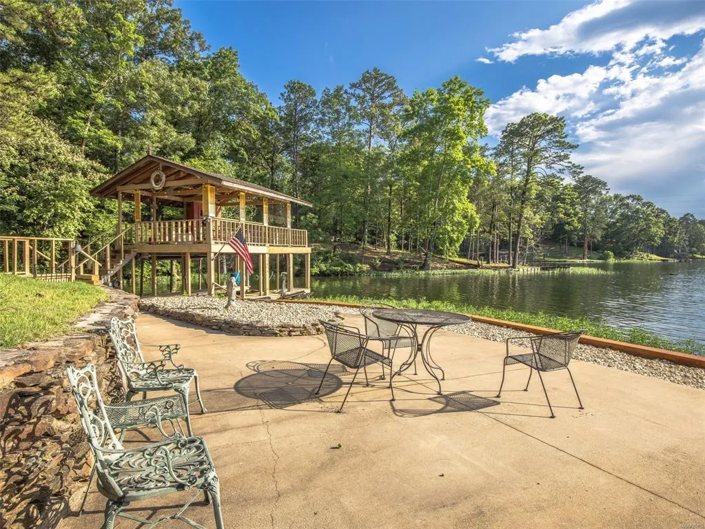 A spacious patio overlooking a serene lake, featuring a private boathouse with a covered deck.