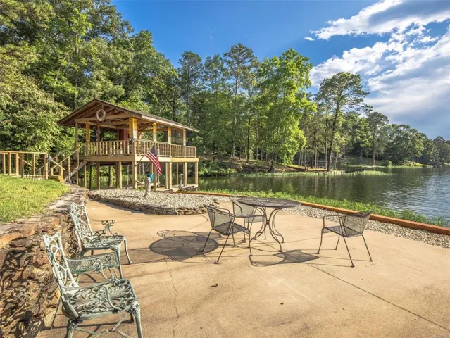 A spacious patio overlooking a serene lake, featuring a private boathouse with a covered deck.