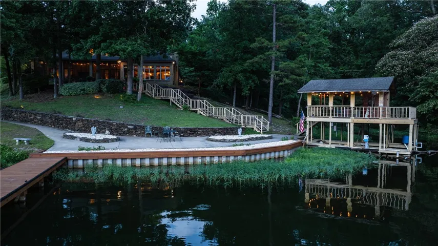 A tranquil lakeside estate features extensive outdoor living space and a private boat dock with an upper-level deck.