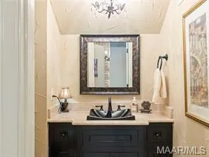 A well-lit powder room offers a striking black vessel sink and elegant dark wood vanity.