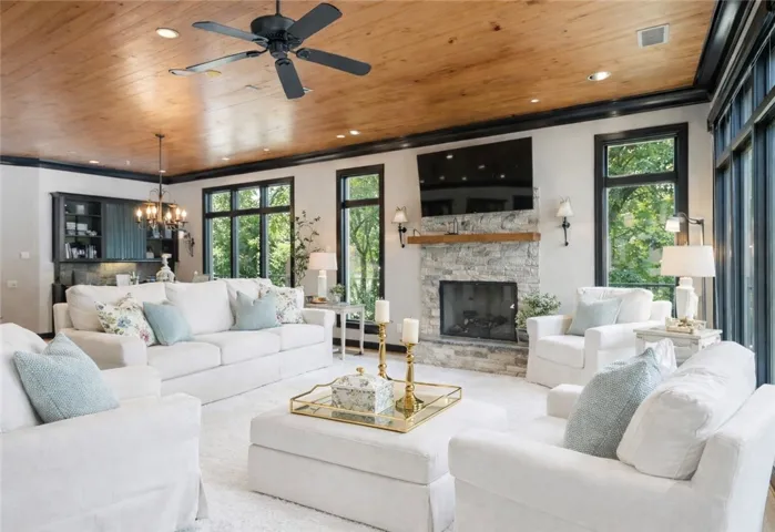 A well-lit living space features a captivating stone fireplace, complementing the natural wood ceiling.