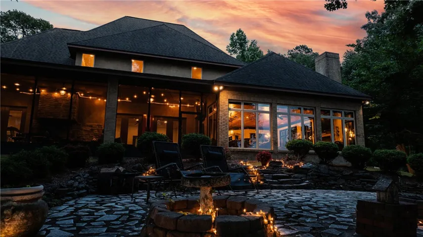 An inviting stone patio with a fire pit awaits outdoor entertaining against a stunning twilight sky.