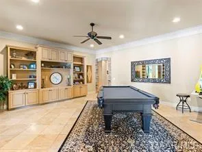An inviting game room features a classic pool table centered on a decorative rug and custom built-in shelving.