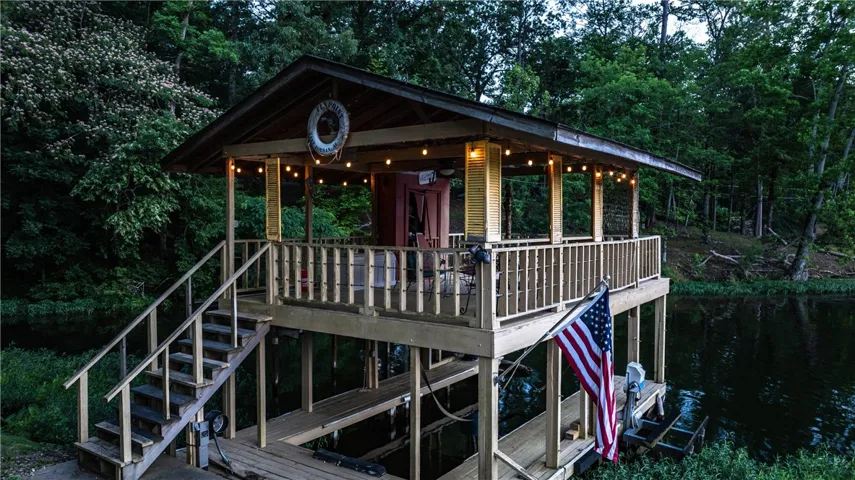 A charming lakefront boathouse with a welcoming covered deck and a convenient dock for water access.