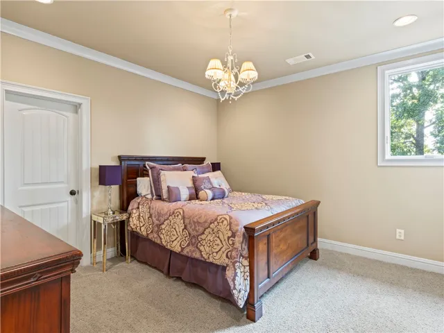 A well-appointed bedroom featuring crown molding and soft carpeted flooring for comfort.