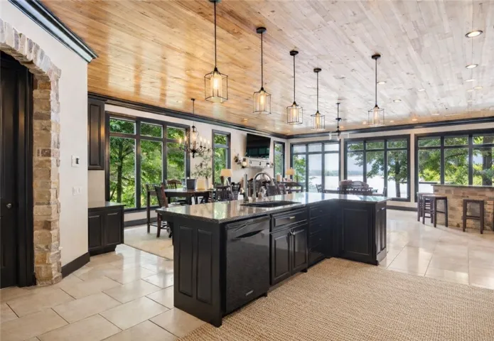 An open concept kitchen features an island, ample seating, and panoramic lake views through vast windows.