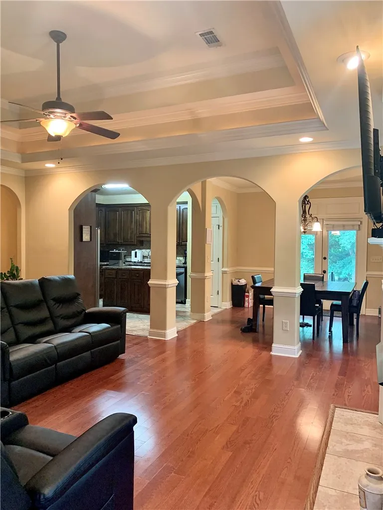 Rich hardwood floors flow through an open-concept living space, leading to a well-appointed kitchen and dining area.