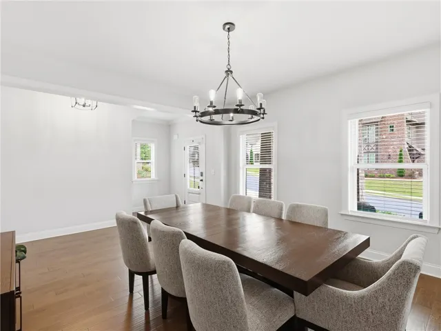 A sophisticated dining room awaits, featuring hardwood floors and an elegant chandelier.