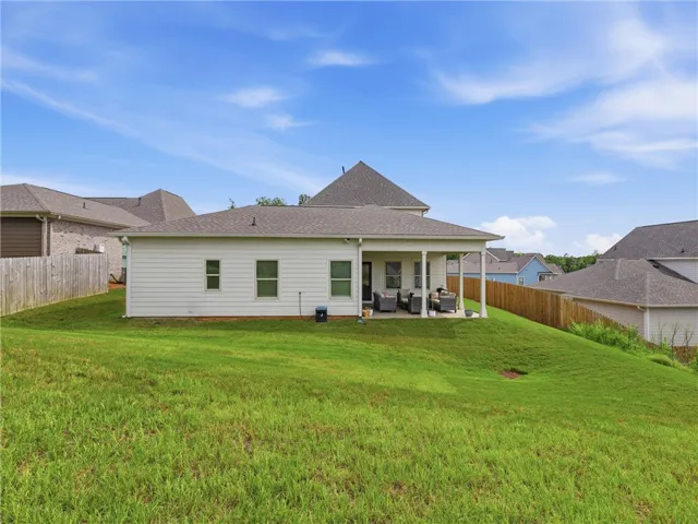 A spacious grassy yard extends behind this inviting home, featuring a shaded patio ideal for outdoor gatherings.