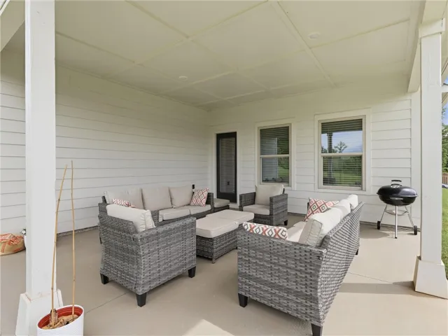 An inviting covered patio, ideal for leisure, features a charcoal grill.
