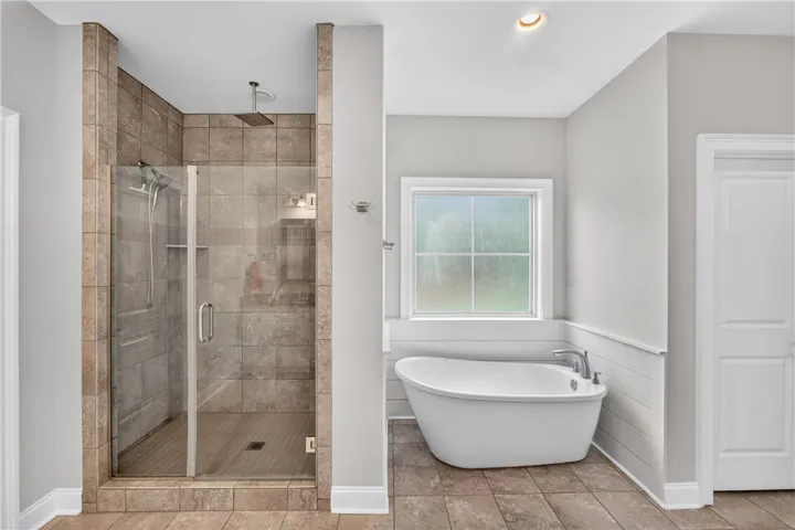 Indulge in a tranquil retreat featuring a spacious tiled shower and a freestanding soaking tub.