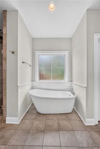 Indulge in relaxation within this primary bathroom, featuring a deep soaking tub by a window.