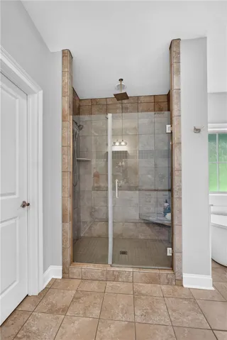 A spacious, glass-enclosed shower featuring elegant tile work and a modern rain showerhead.