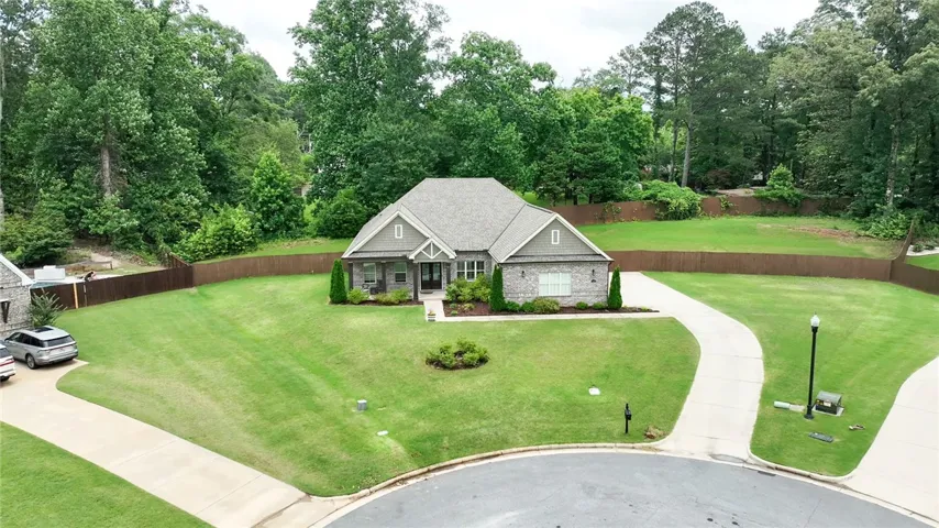 A neatly manicured lawn embraces this charming residence, framed by mature trees and a privacy fence.