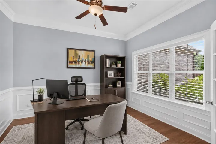 A refined home office with crown molding and abundant natural light offers a tranquil work environment. Virtually staged