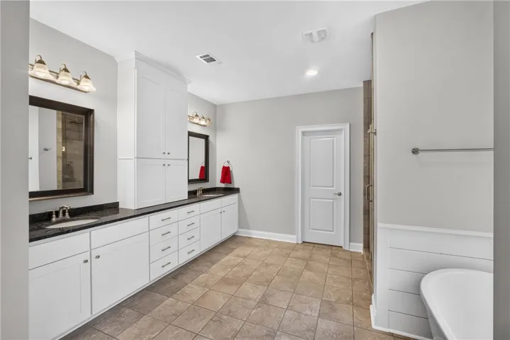 Dual vanities with granite counters complement the generously sized tile-floored primary bathroom.