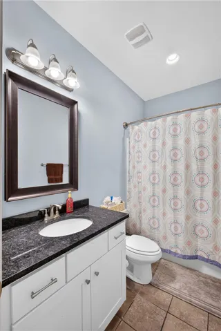 A well-appointed bathroom offers a stylish granite counter vanity and ample lighting.