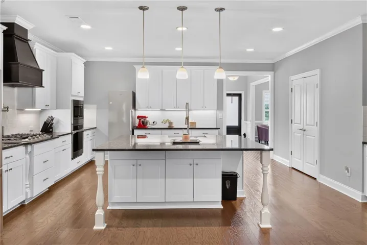 A well-appointed kitchen features rich hardwood flooring and a functional island with integrated sink.