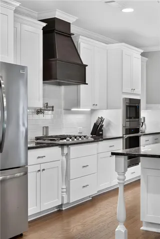 A well-equipped kitchen boasts gleaming hardwood flooring, white cabinetry, and stainless steel appliances.