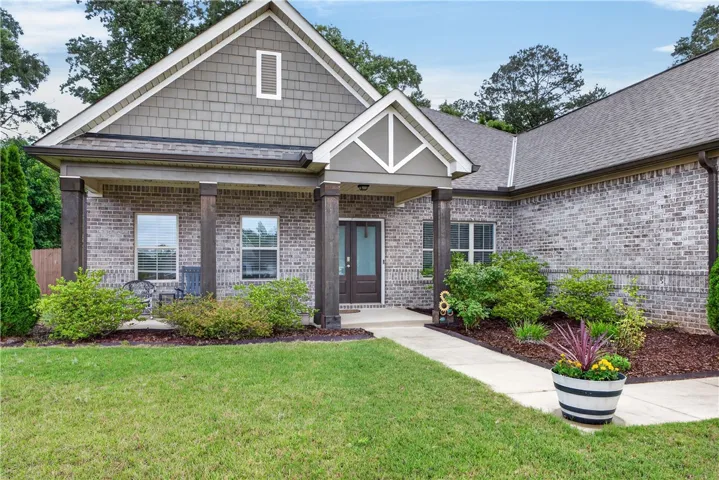A welcoming front exterior showcasing a blend of brick and shingle siding with mature landscaping and a well-maintained lawn.