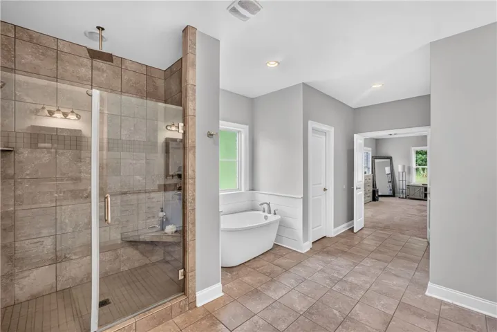 Unwind in the primary bath, featuring a generous walk-in shower and a freestanding soaking tub.