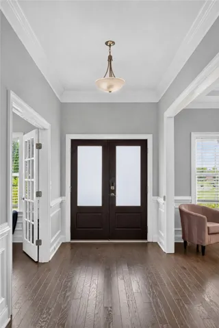 A well-lit entry hall with crown molding and polished hardwood flooring greets you upon arrival.