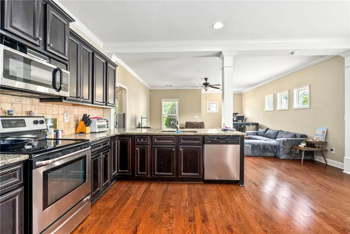 A warm, open-concept kitchen flows into a sun-drenched living area, featuring rich wood floors and contemporary fixtures.